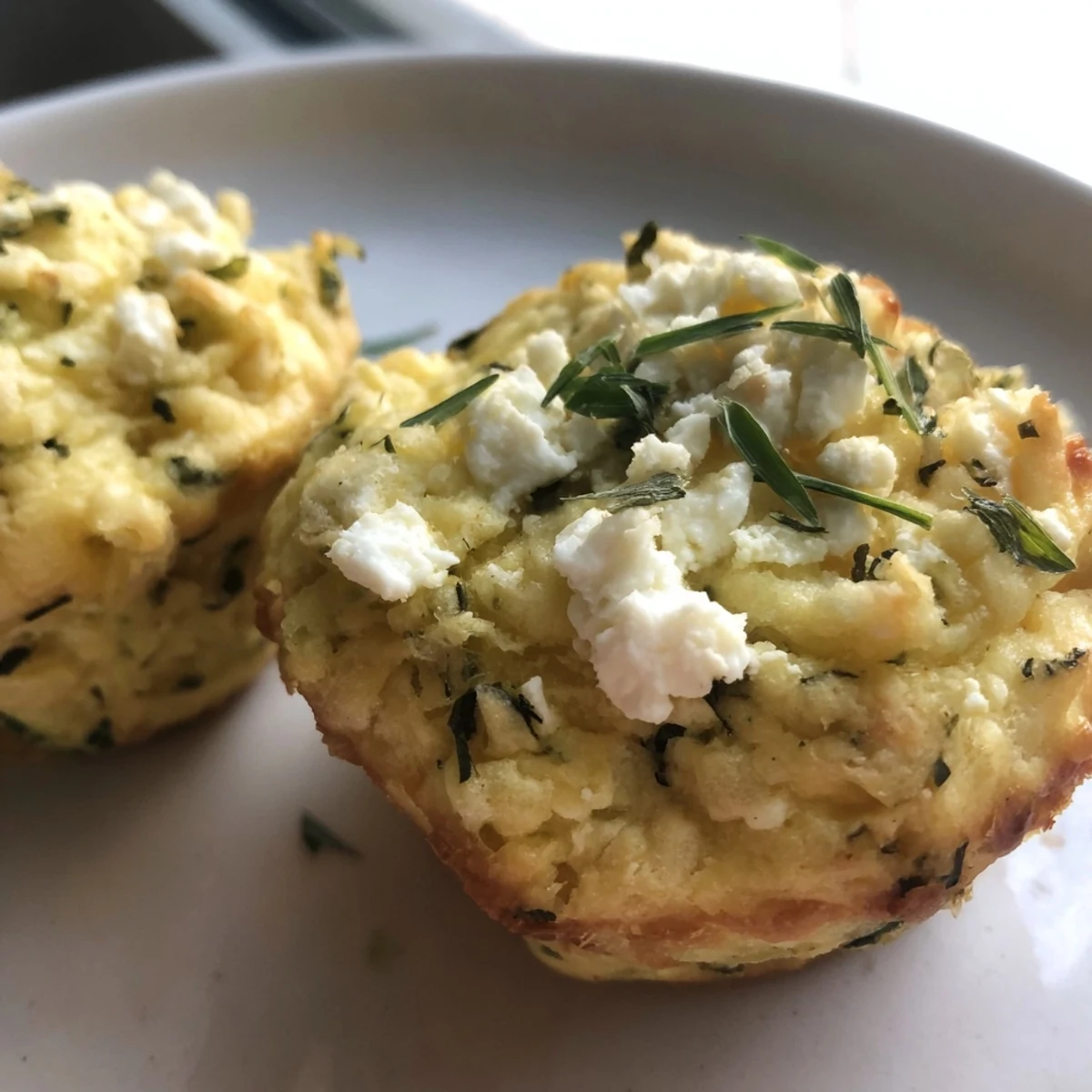 Golden-brown Savory Zucchini and Feta Muffins, fresh from the oven, ready to enjoy as a snack.