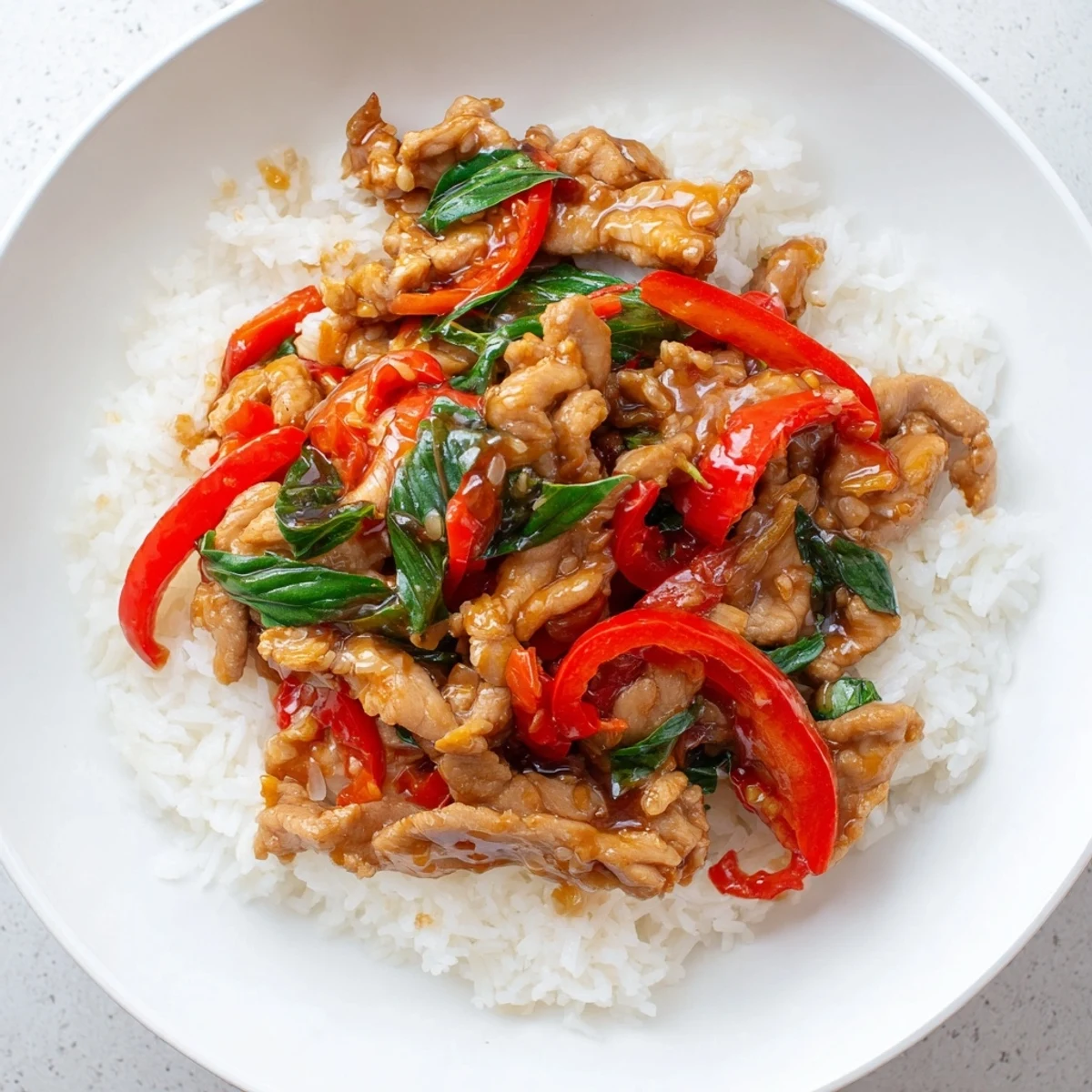 Close-up of savory Thai Basil Chicken Bowls in a bowl, showcasing the tender chicken and spicy peppers.