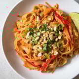 Close-up of perfectly coated spicy peanut noodles, garnished with fresh cilantro and crunchy peanuts.