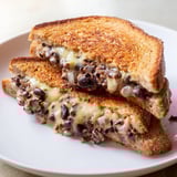 A close-up of a warm, cheesy Black Bean Grilled Cheese sandwich, sliced in half, showing filling.