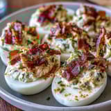 Creamy jalapeño popper deviled eggs featuring tangy cream cheese, smoky bacon, and fresh jalapeño slices.