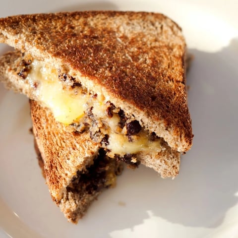 Golden-brown Black Bean Grilled Cheese, with melted cheese oozing onto the plate, ready to eat.