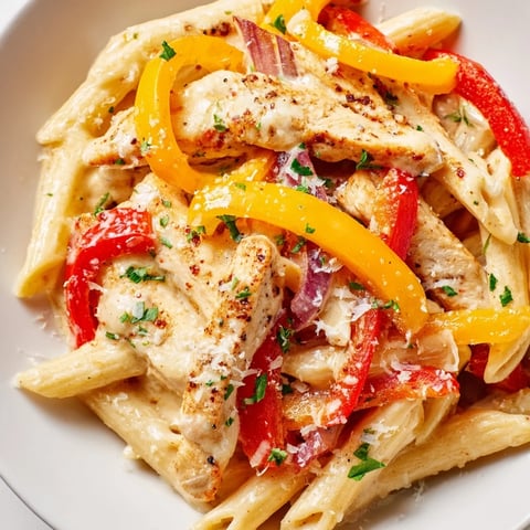 Cajun Chicken Pasta with creamy sauce, colorful peppers, and parsley garnish looks delicious.