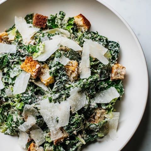 Close-up photo of a delicious Kale Caesar Salad with perfectly toasted homemade croutons and shaved cheese.