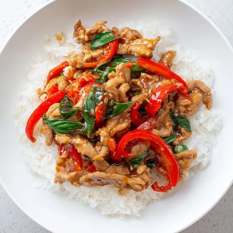 Close-up of savory Thai Basil Chicken Bowls in a bowl, showcasing the tender chicken and spicy peppers.