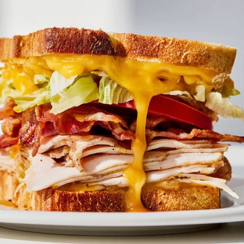 This hearty Turkey Club Grilled Cheese features toasted sourdough, smoky bacon, and melted cheese, sliced to reveal layers of roasted turkey and crisp veggies.  