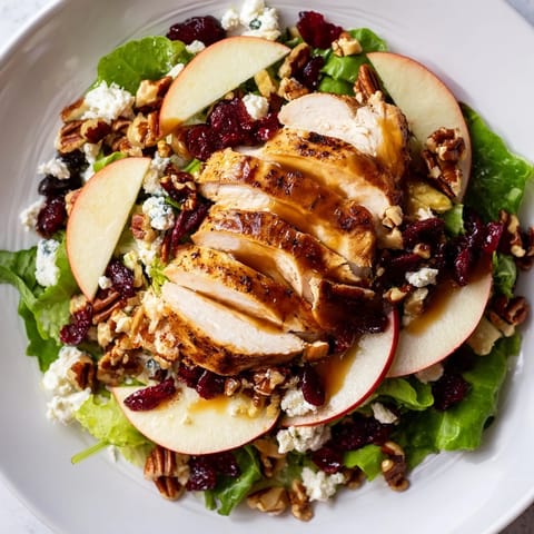 A hearty Caramel Apple Chicken Salad with golden-brown chicken, red onion, and dried cranberries on a platter.  