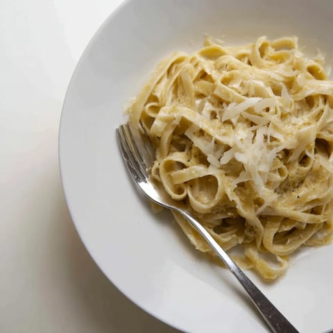 Silky roasted garlic cream sauce coats al dente fettuccine, paired with a glass of white wine.  