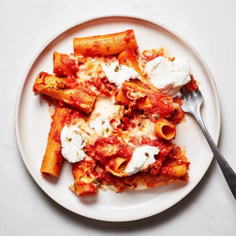 Freshly baked ziti topped with melted cheese and herbs, served hot from the oven for a comforting family dinner.  