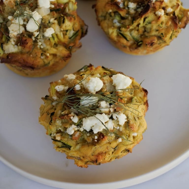 A close-up image showcases fluffy Savory Zucchini and Feta Muffins, perfectly baked and bursting with flavor.