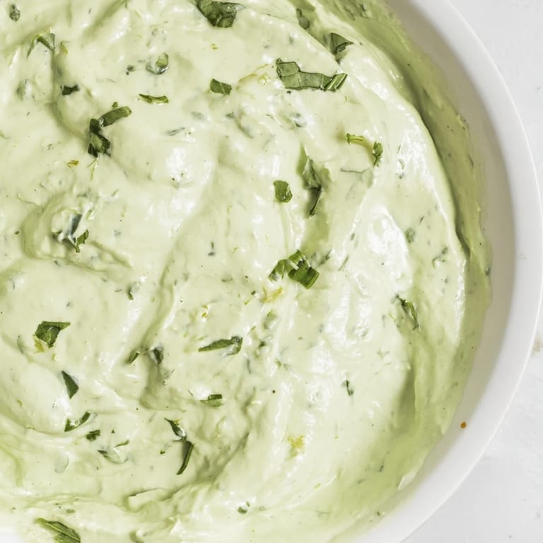 Green Goddess Salad Dip surrounded by colorful crudités like bell peppers, cucumbers, and carrots, perfect for dipping.