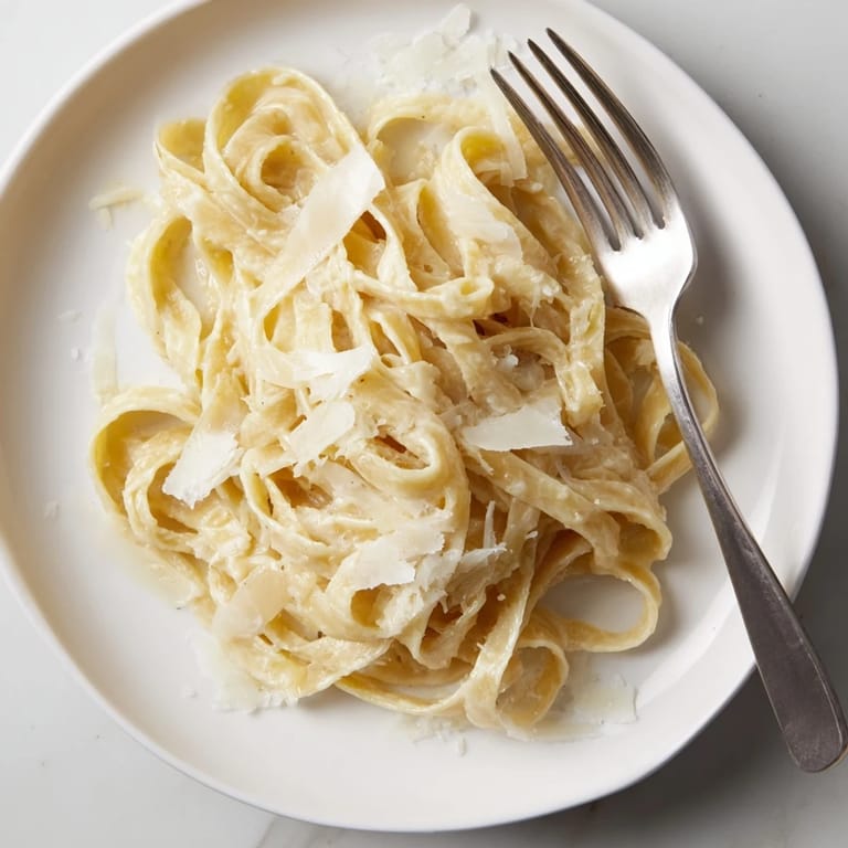 Savory roasted garlic pasta twirled on a fork, steaming on a white plate for dinner.