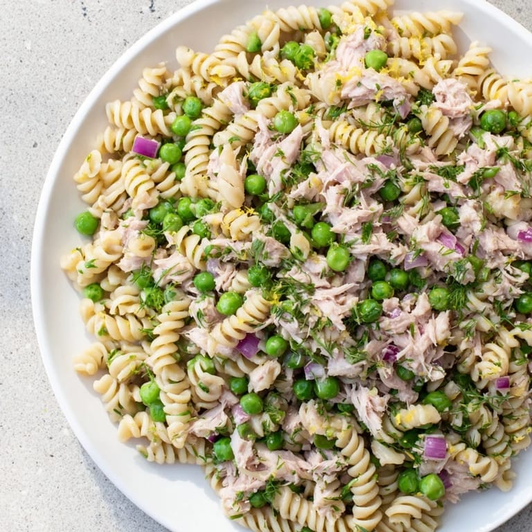 Close-up view of Lemony Tuna Pasta Salad, highlighting al dente fusilli, sweet peas, and a glistening olive oil and lemon sauce.