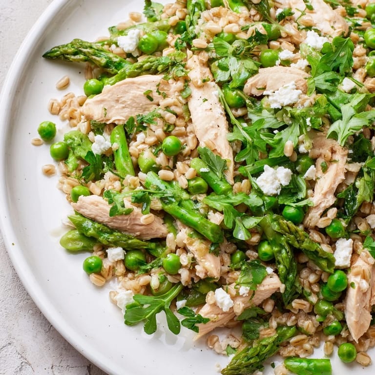 Sunlit plate of Warm Spring Farro Chicken Salad featuring tender grains, crisp vegetables, and crumbled feta cheese, ready for a light meal.  