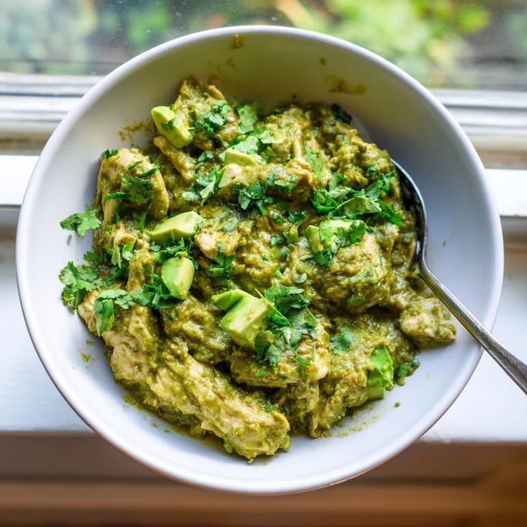 Steaming Chicken Chili Verde served over rice with warm corn tortillas and a sprinkle of cilantro on a wooden table.