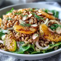 A bowl of Farro Salad with Fennel, Oranges & Almonds showcases crisp shaved fennel and bright citrus segments on fluffy grains.