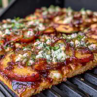 Grilled flatbread with BBQ sauce, melted Brie, and sweet peaches topped with fresh basil and arugula.